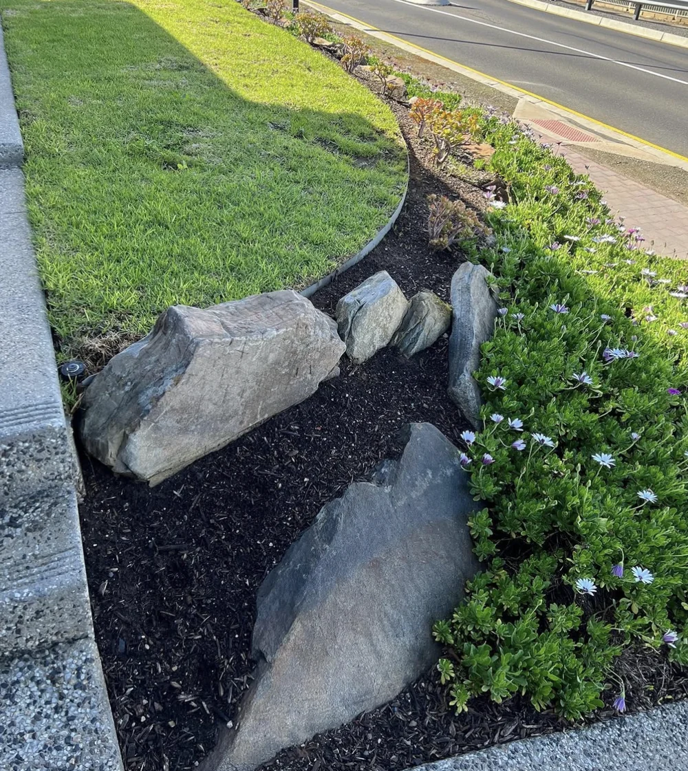 Natural boulder retaining edge with lawn and planting